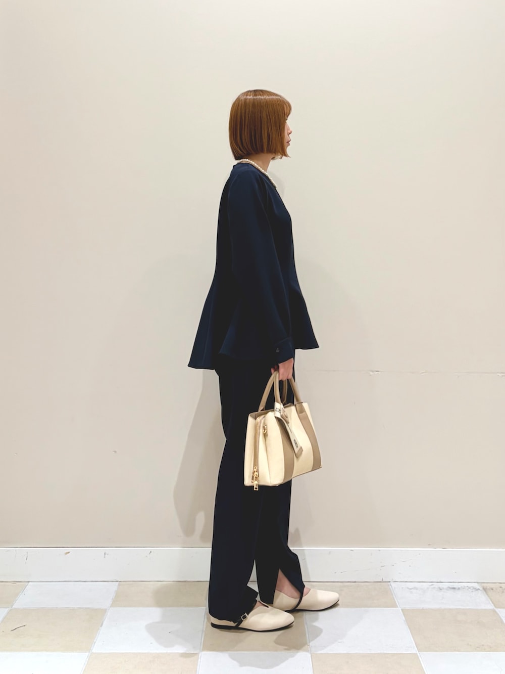 ホワイト系のハンドバッグ、ブルー系のセットアップ、ホワイト系のネックレスを着用したレディースの春コーディネートの2枚目の写真