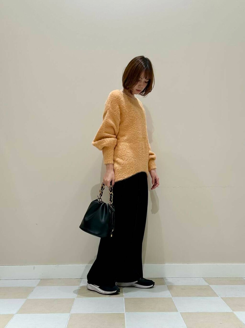 ブラック系のその他パンツ、ブラック系のショルダーバッグ、オレンジ系のニット/セーターを着用したレディースの冬コーディネートの2枚目の写真