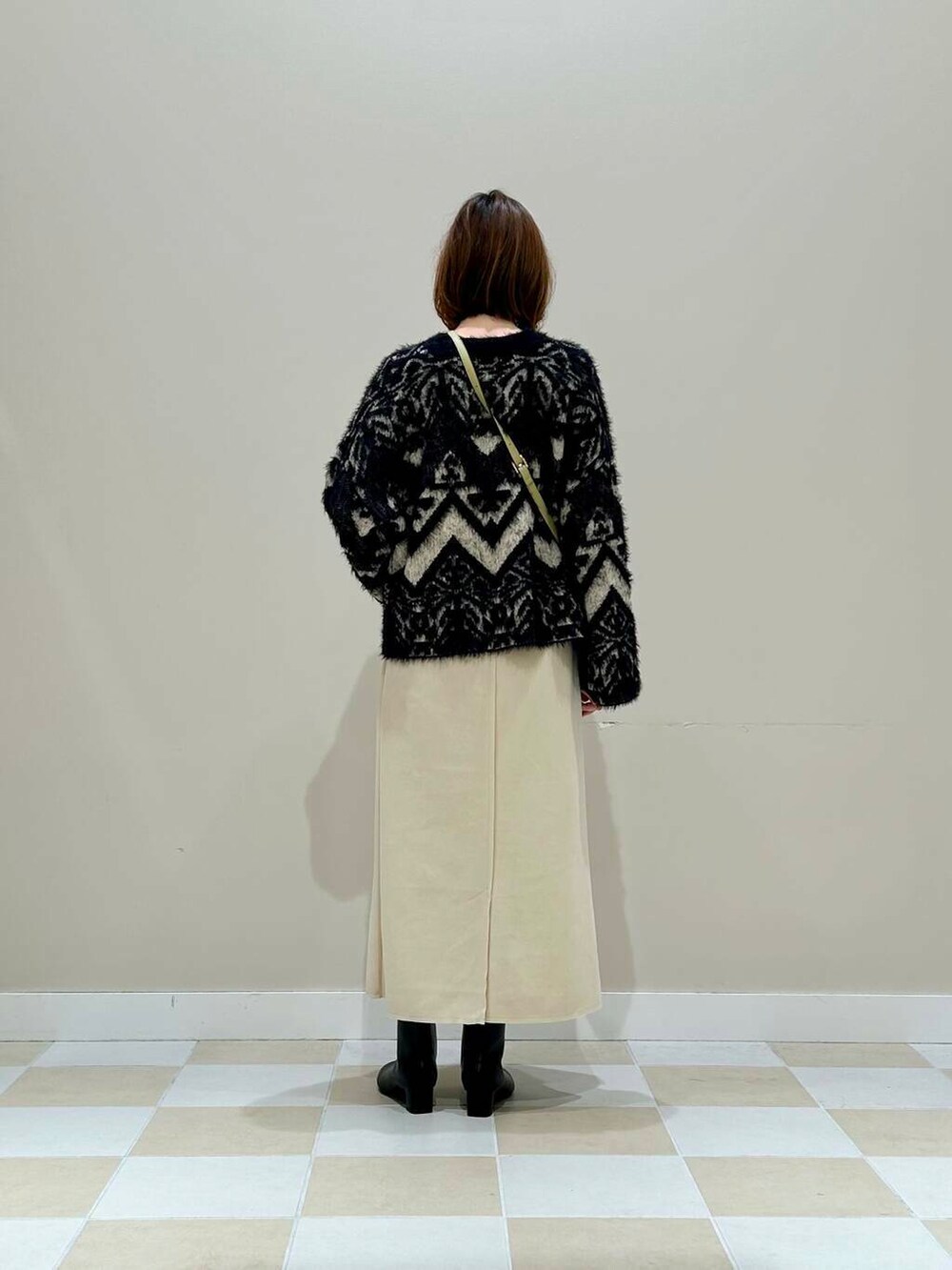 ブラック系のブーツ、グリーン系のショルダーバッグ、ホワイト系のスカートを着用したレディースの冬コーディネートの3枚目の写真