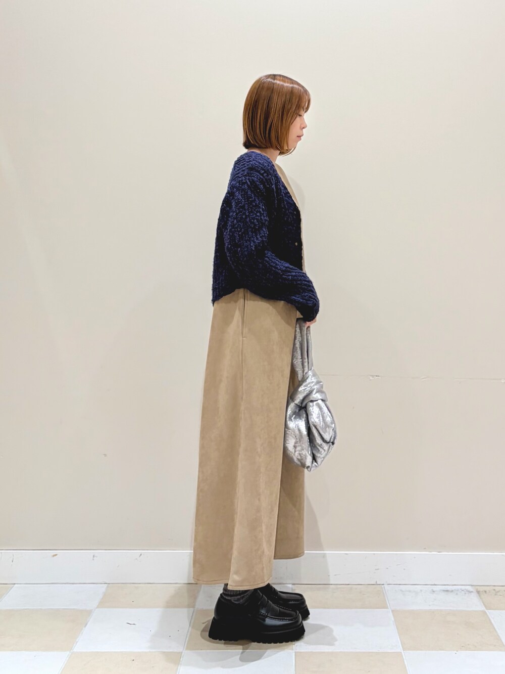 ブルー系のニット/セーター、ブラウン系のワンピース、ゴールド系のハンドバッグを着用したレディースの冬コーディネートの2枚目の写真