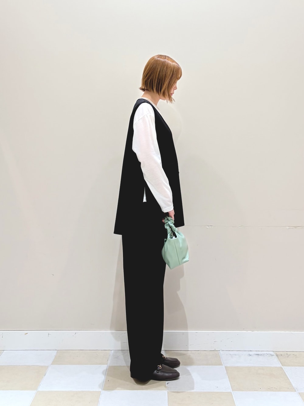 ブラック系のセットアップ、グリーン系のショルダーバッグ、ホワイト系のネックレスを着用したレディースの冬コーディネートの2枚目の写真