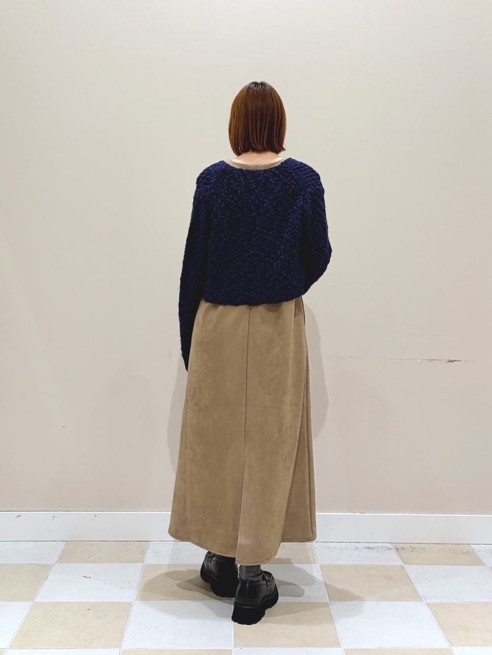 ブルー系のニット/セーター、ブラウン系のワンピース、ゴールド系のハンドバッグを着用したレディースの冬コーディネートの3枚目の写真