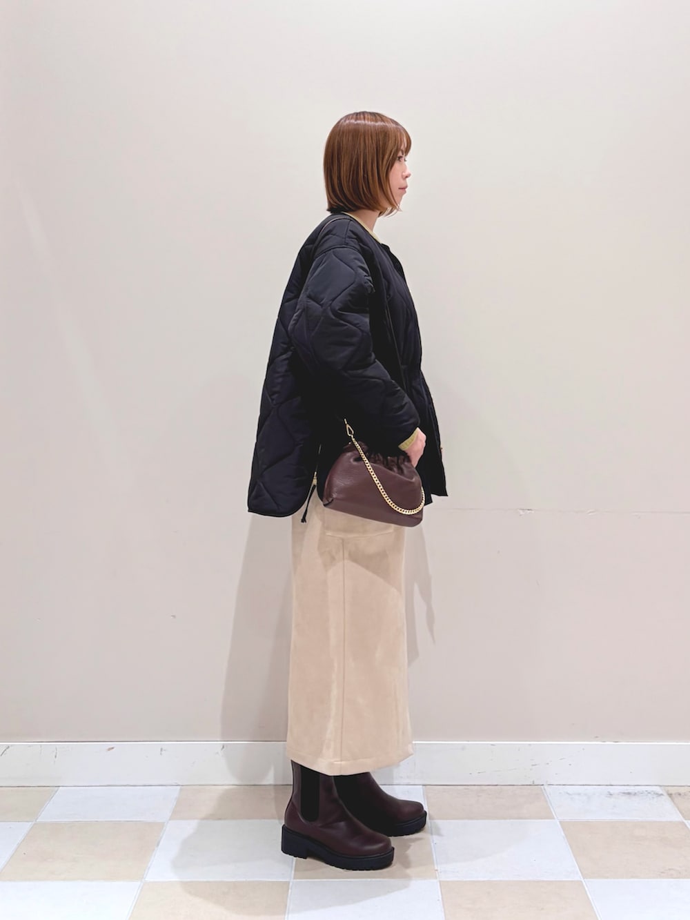 ブラック系のブルゾン、ホワイト系のスカート、ブラウン系のブーツを着用したレディースの冬コーディネートの2枚目の写真