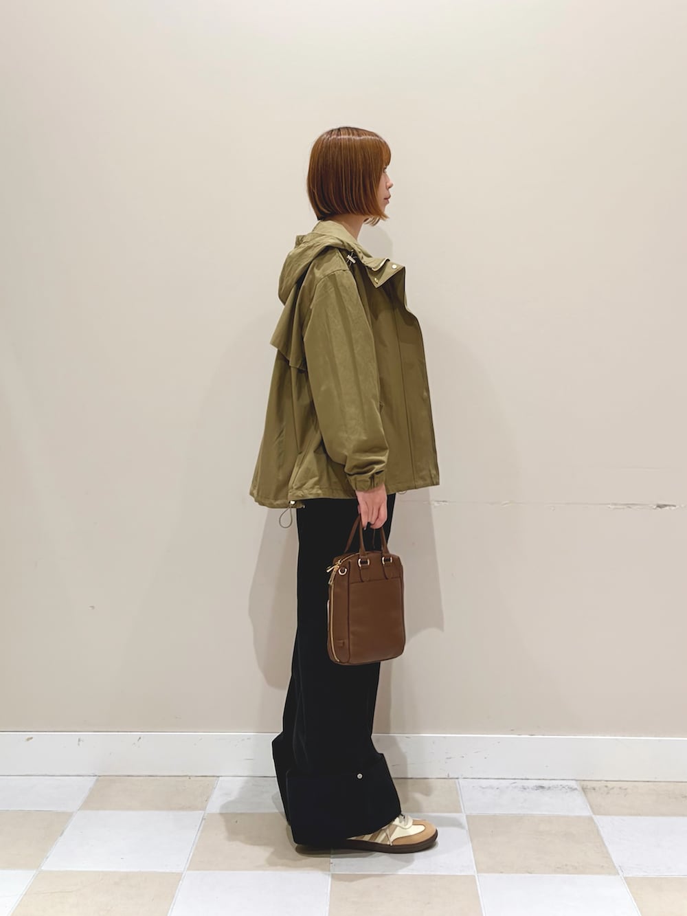 ホワイト系のニット/セーター、ブラック系のその他パンツ、ベージュ系のマウンテンパーカーを着用したレディースの春コーディネートの2枚目の写真