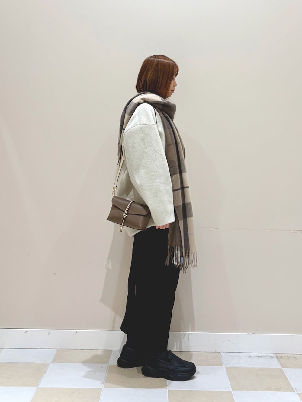 ホワイト系のノーカラージャケット、ブラック系のスカート、ブラウン系のマフラーを着用したレディースの冬コーディネートの2枚目の写真