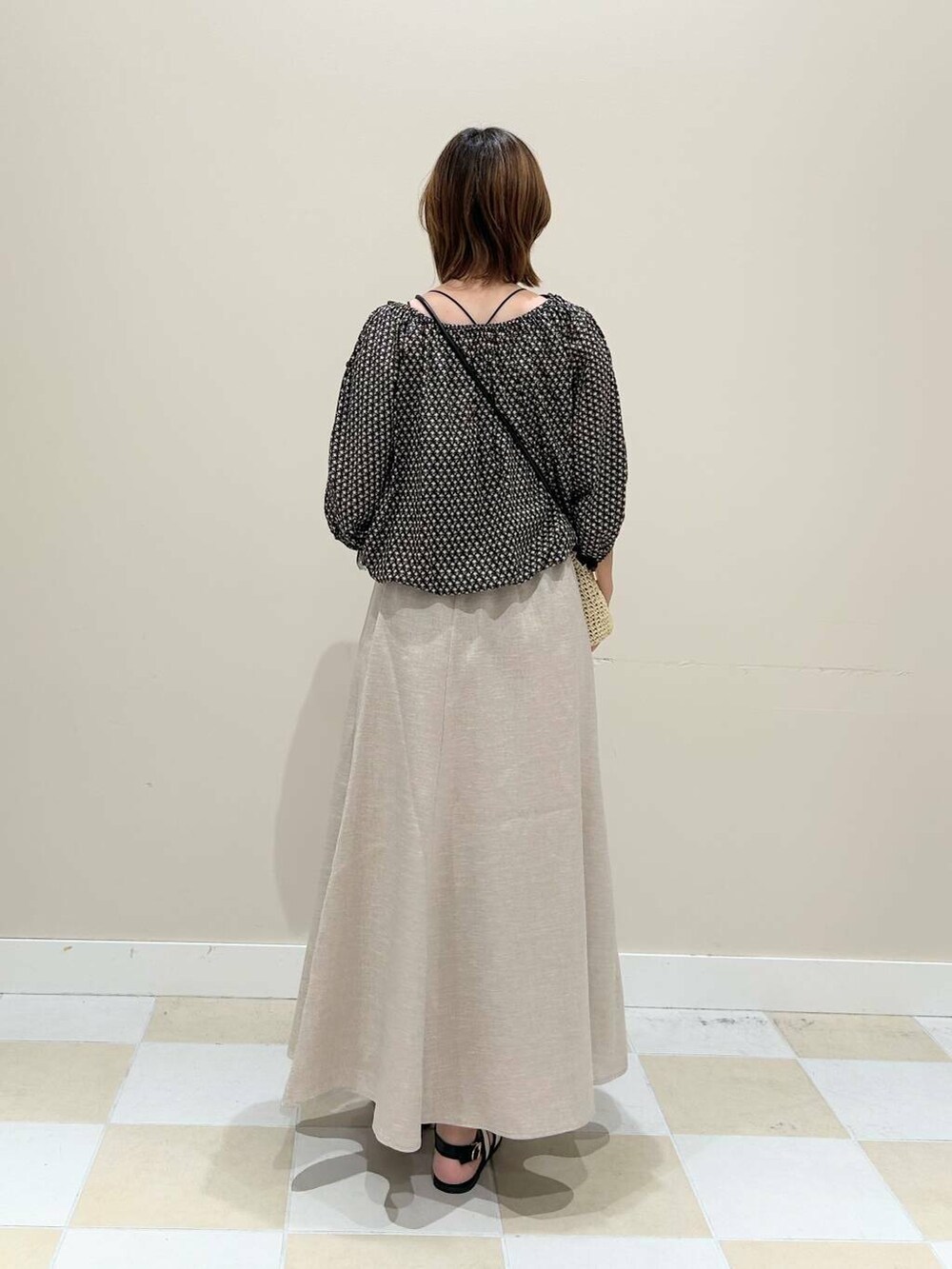 ベージュ系のショルダーバッグ、ベージュ系のスカート、ブラック系のシャツ/ブラウスを着用したレディースの夏コーディネートの3枚目の写真