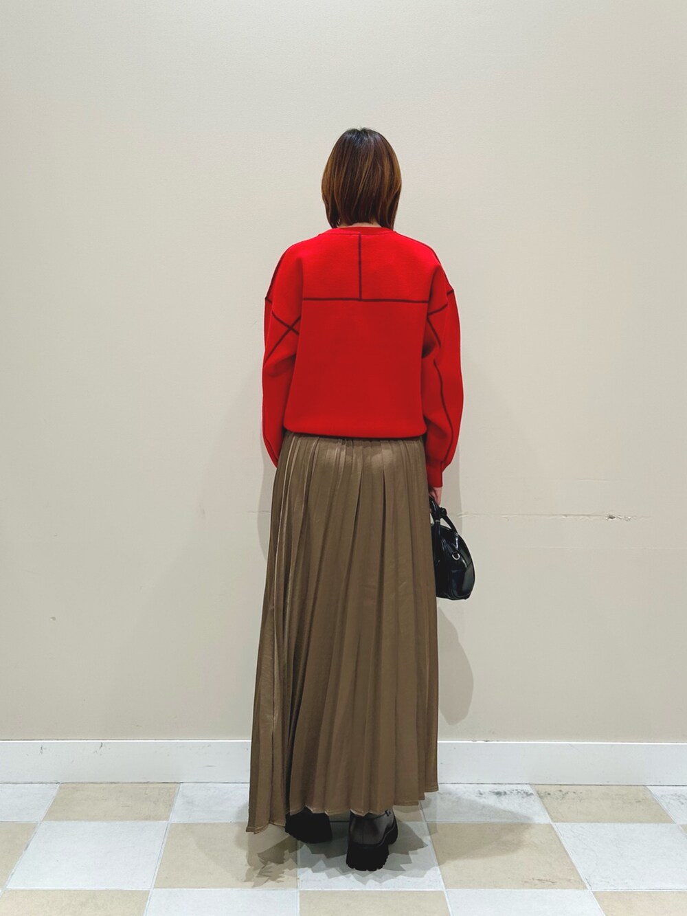 レッド系のニット/セーター、ブラウン系のスカート、ブラック系のボストンバッグを着用したレディースの秋コーディネートの3枚目の写真