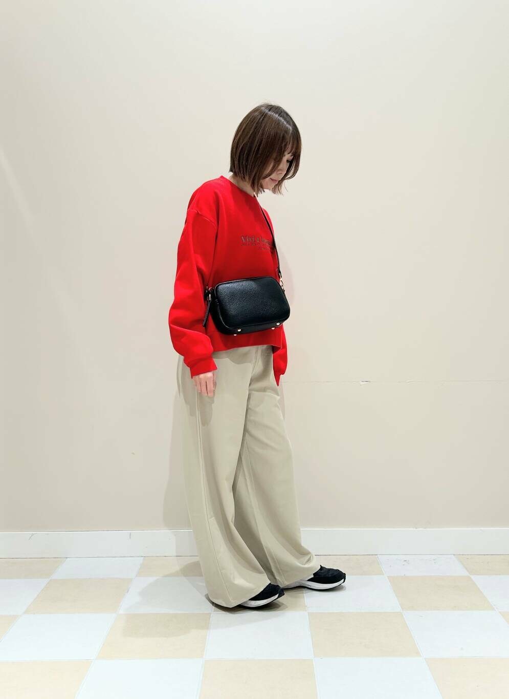 ブラック系のショルダーバッグ、ベージュ系のその他パンツ、レッド系のTシャツ/カットソーを着用したレディースの冬コーディネートの2枚目の写真