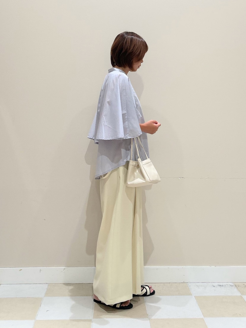 ブルー系のシャツ/ブラウス、ホワイト系のハンドバッグを着用したレディースの夏コーディネートの2枚目の写真