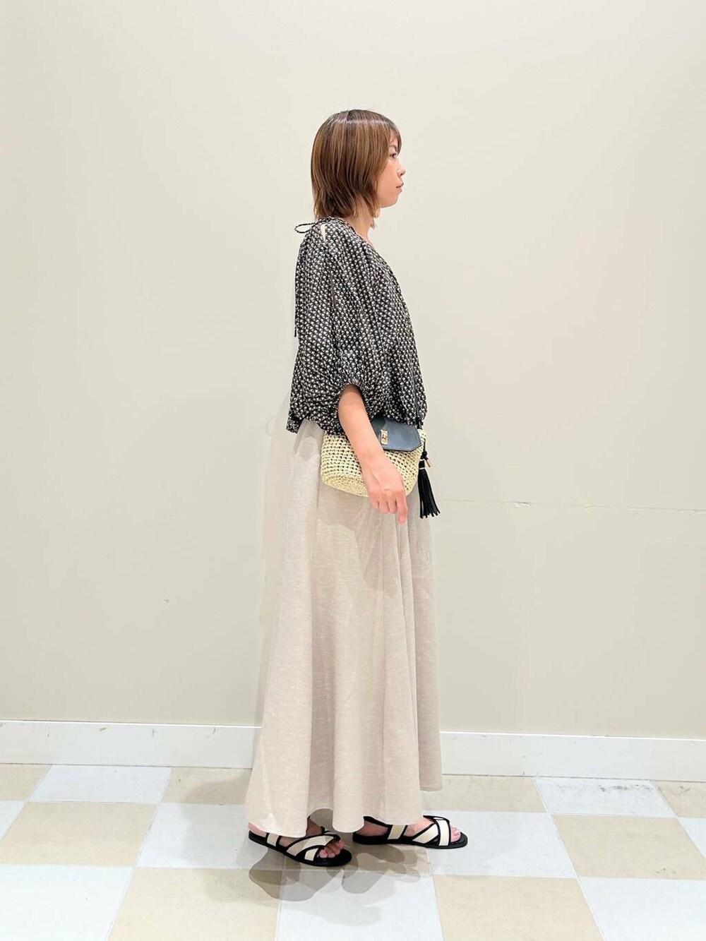 ベージュ系のショルダーバッグ、ベージュ系のスカート、ブラック系のシャツ/ブラウスを着用したレディースの夏コーディネートの2枚目の写真