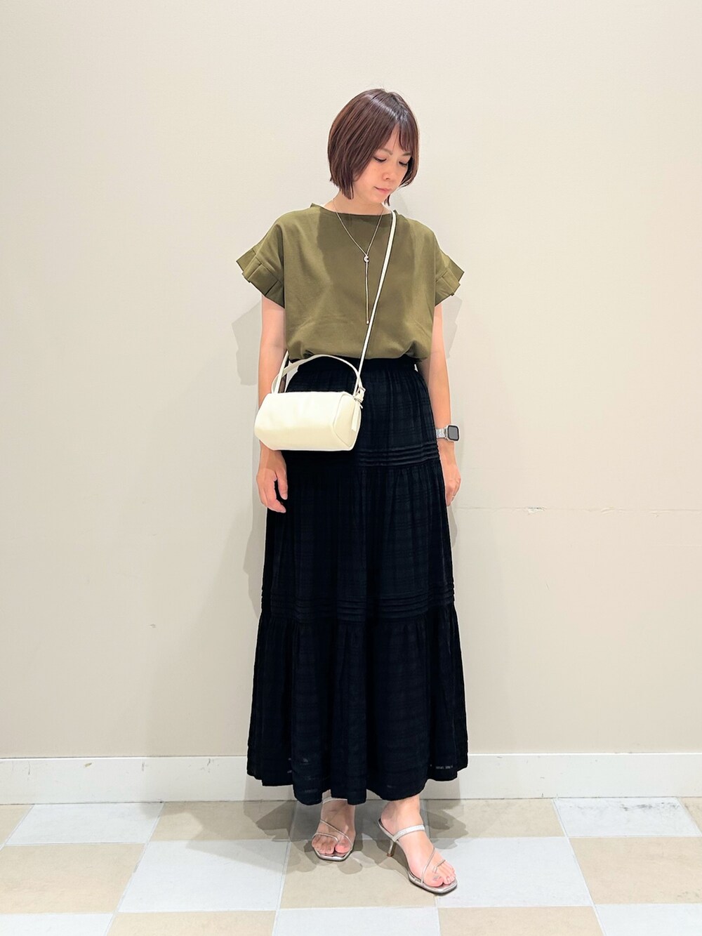 ブラック系のスカート、グリーン系のTシャツ/カットソー、シルバー系のネックレスを着用したレディースの夏コーディネートの2枚目の写真