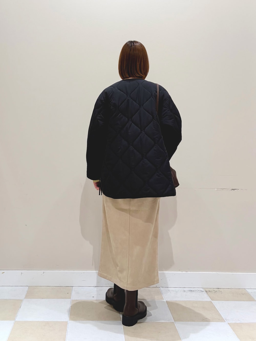 ブラック系のブルゾン、ホワイト系のスカート、ブラウン系のブーツを着用したレディースの冬コーディネートの3枚目の写真