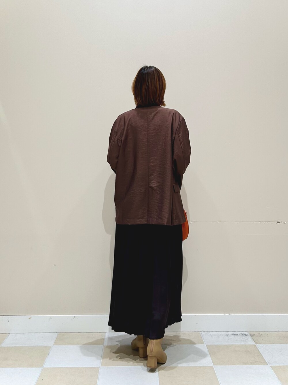 オレンジ系のショルダーバッグ、グレー系のスカート、ブラウン系のその他アウターを着用したレディースの秋コーディネートの3枚目の写真