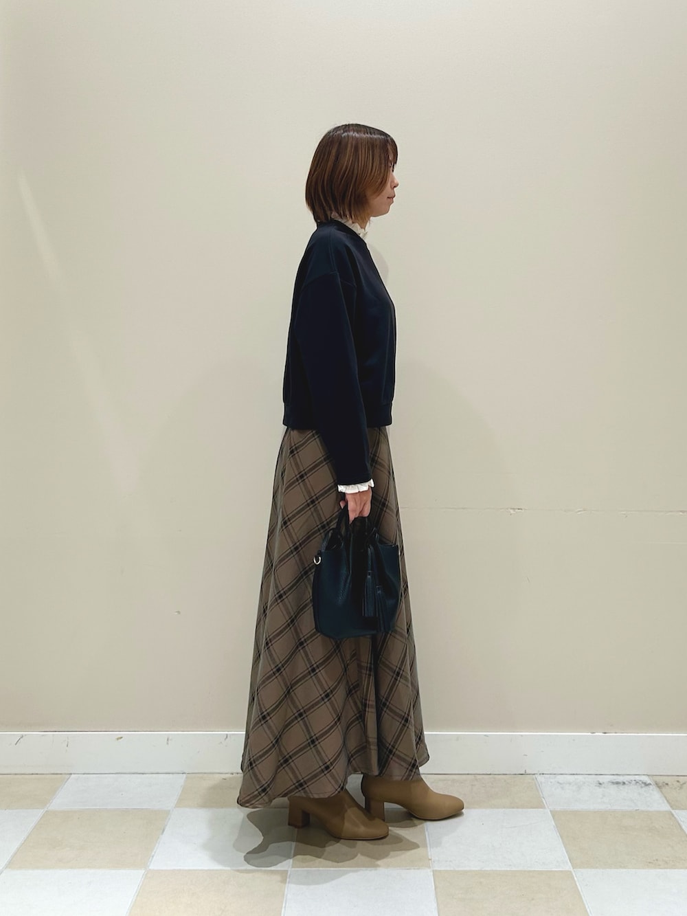 ブラック系のスウェット、ブラウン系のスカート、ブラック系のショルダーバッグを着用したレディースの秋コーディネートの2枚目の写真