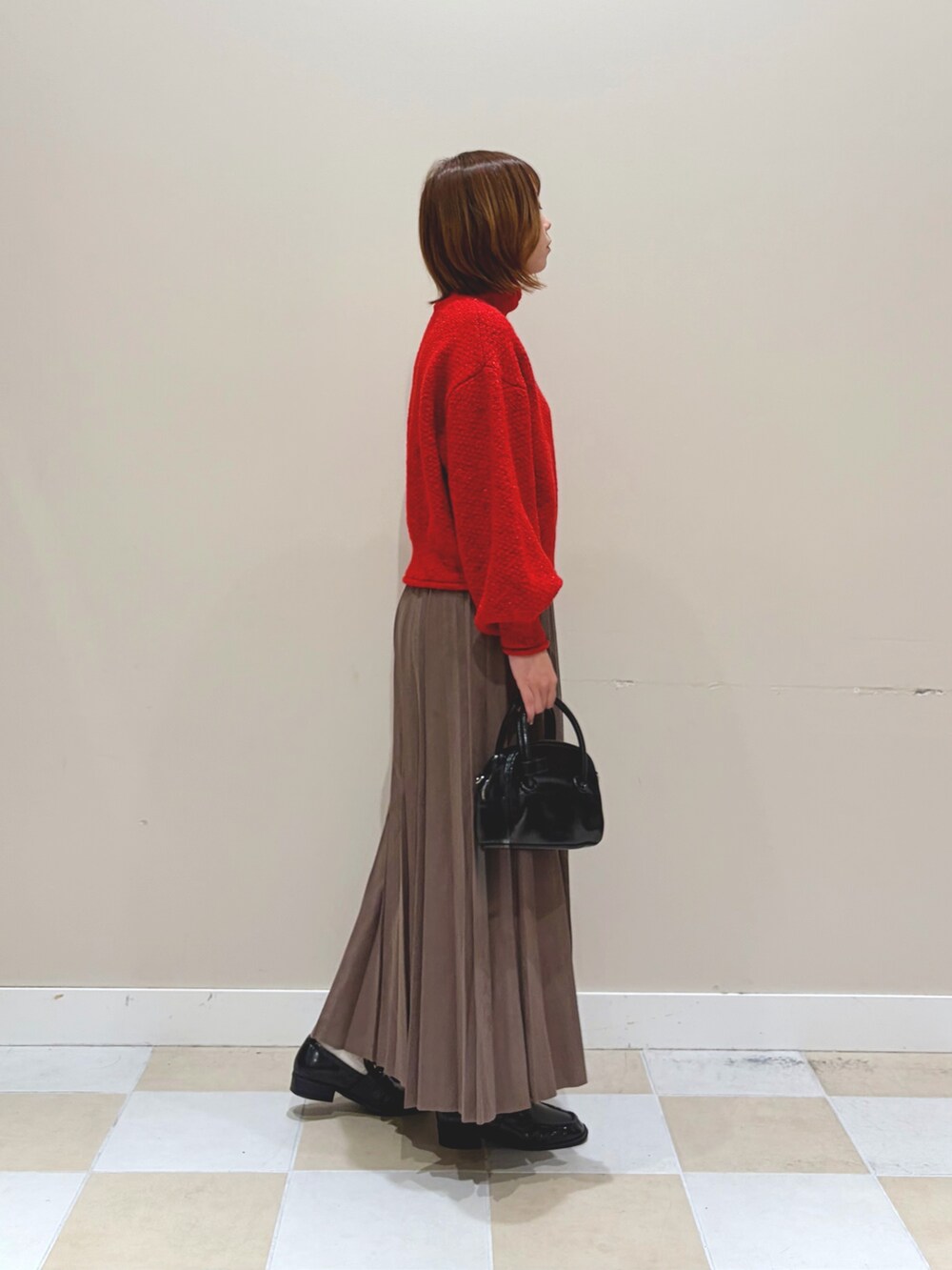 レッド系のニット/セーター、ブラウン系のスカートを着用したレディースの秋コーディネートの2枚目の写真
