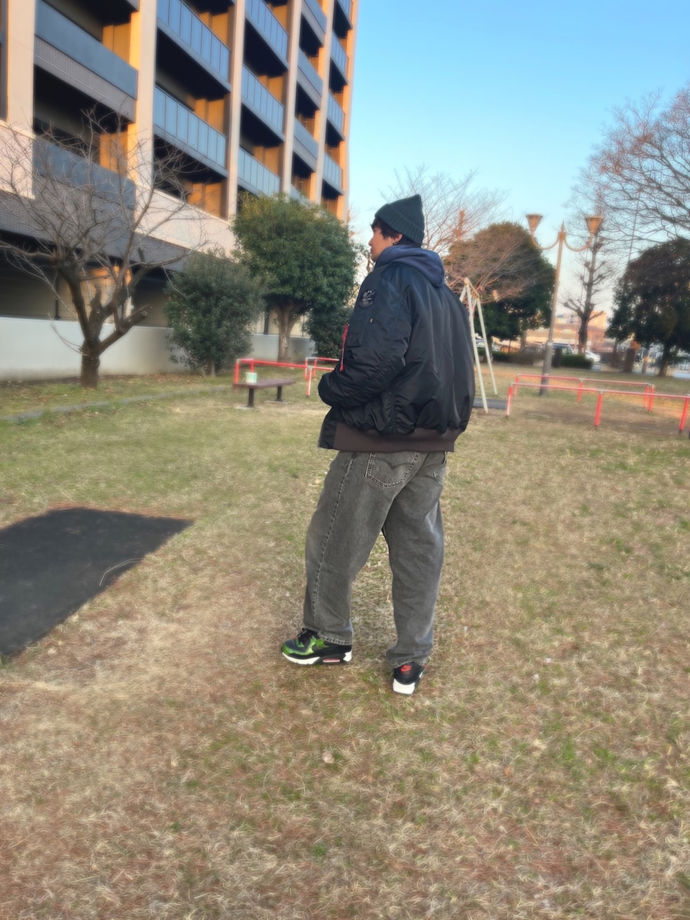 ブルー系のパーカー、ブラック系のMA-1、グリーン系のベストを着用したメンズの冬コーディネートの2枚目の写真