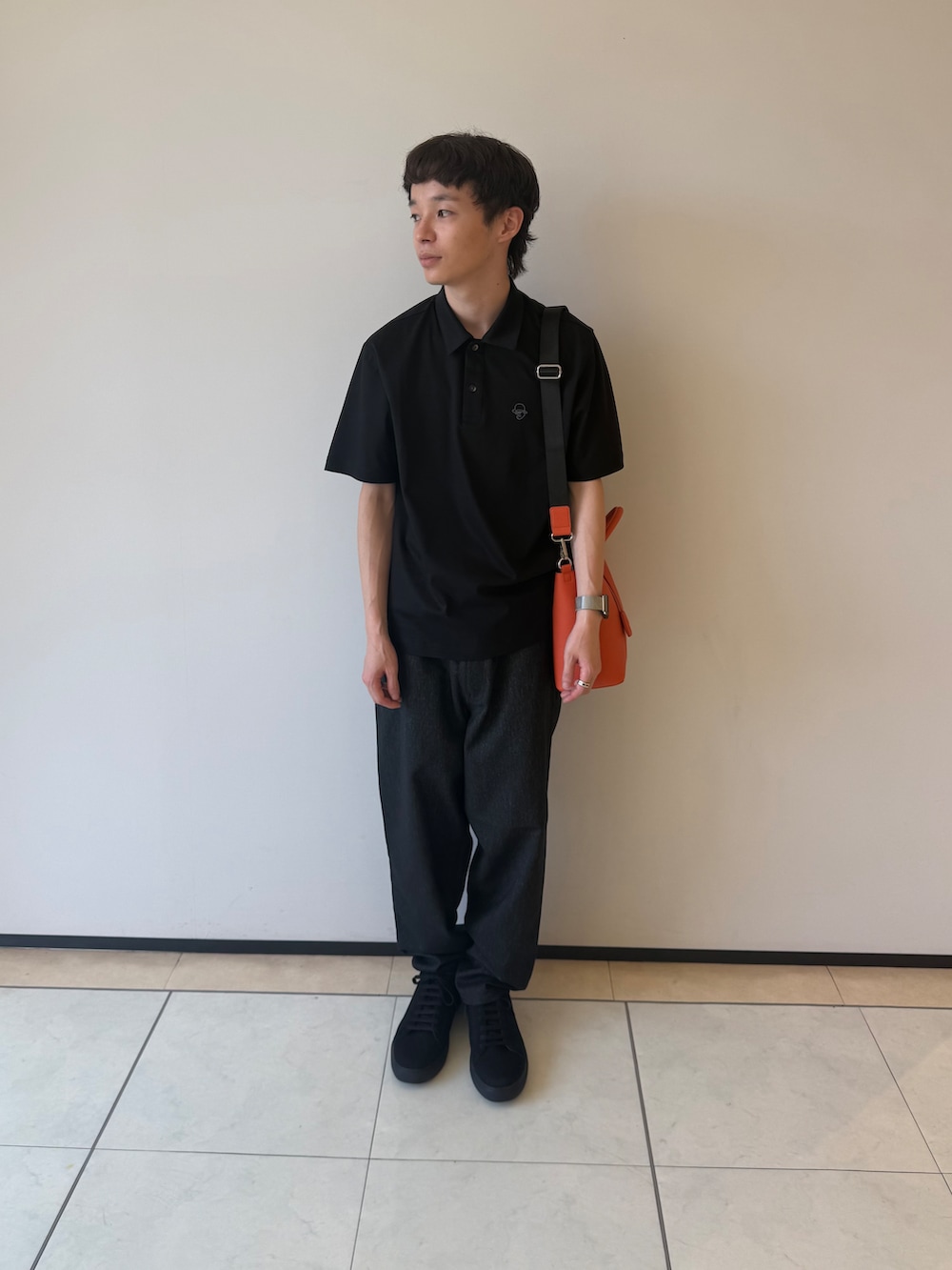 ブラック系のポロシャツ、ブラック系のデニムパンツ、ブラック系のスニーカーを着用したメンズの夏コーディネートの2枚目の写真
