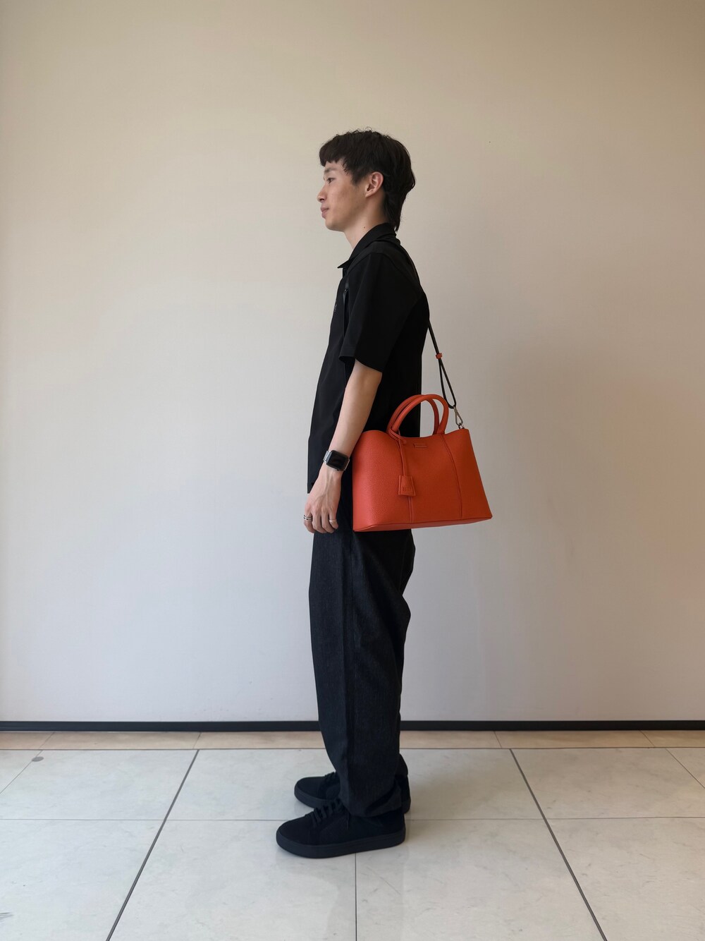 ブラック系のポロシャツ、ブラック系のデニムパンツ、ブラック系のスニーカーを着用したメンズの夏コーディネートの3枚目の写真