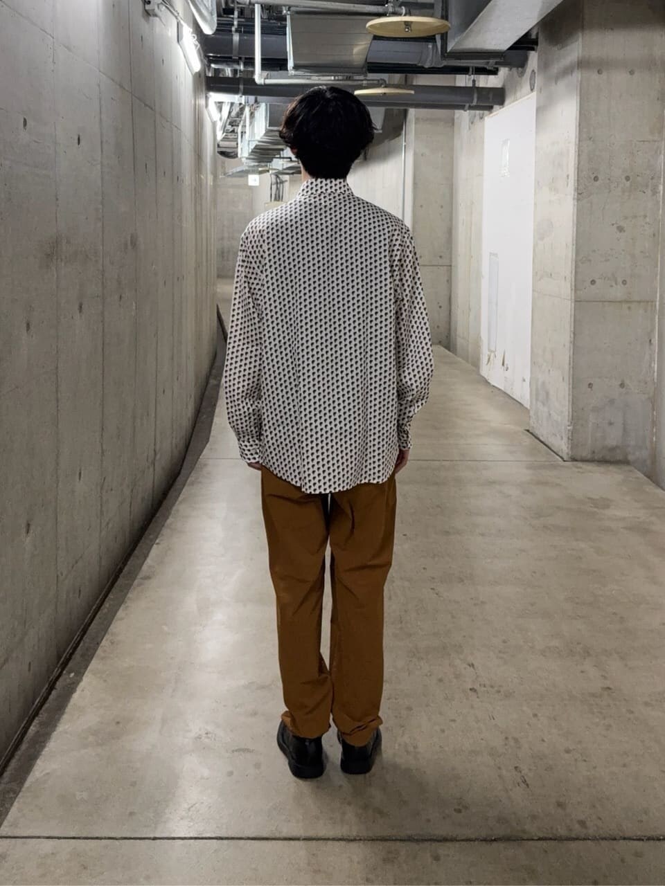 ベージュ系のシャツ/ブラウス、ブラウン系のスラックス、ブラウン系のクラッチバッグを着用したメンズの秋コーディネートの4枚目の写真