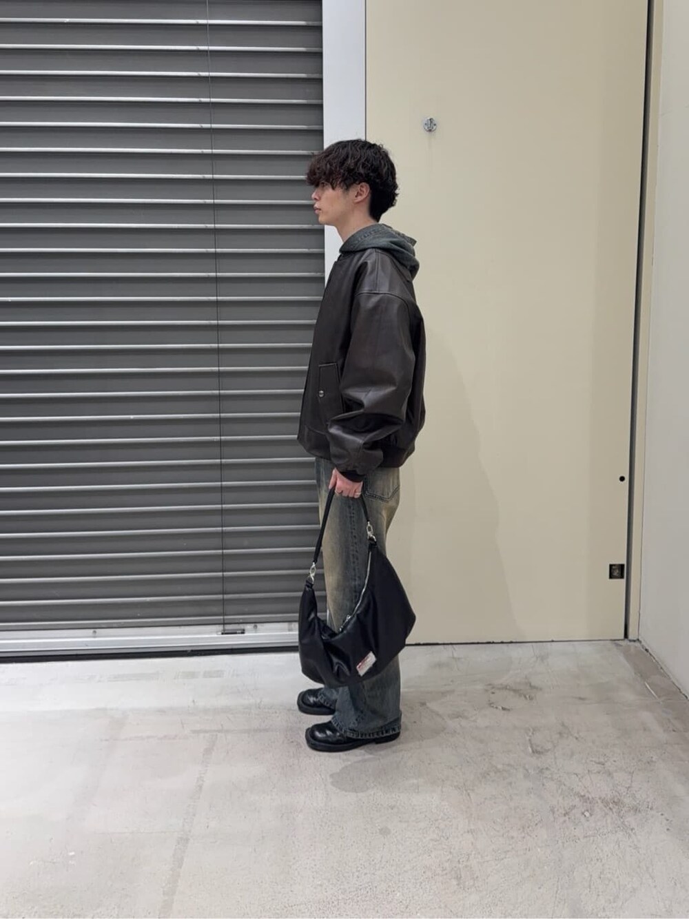 ブラウン系のブルゾン、ブルー系のパーカー、ブルー系のデニムパンツを着用したメンズの秋コーディネートの4枚目の写真