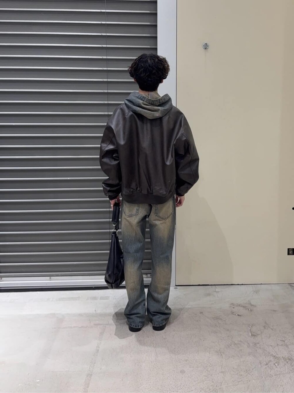 ブラウン系のブルゾン、ブルー系のパーカー、ブルー系のデニムパンツを着用したメンズの秋コーディネートの5枚目の写真
