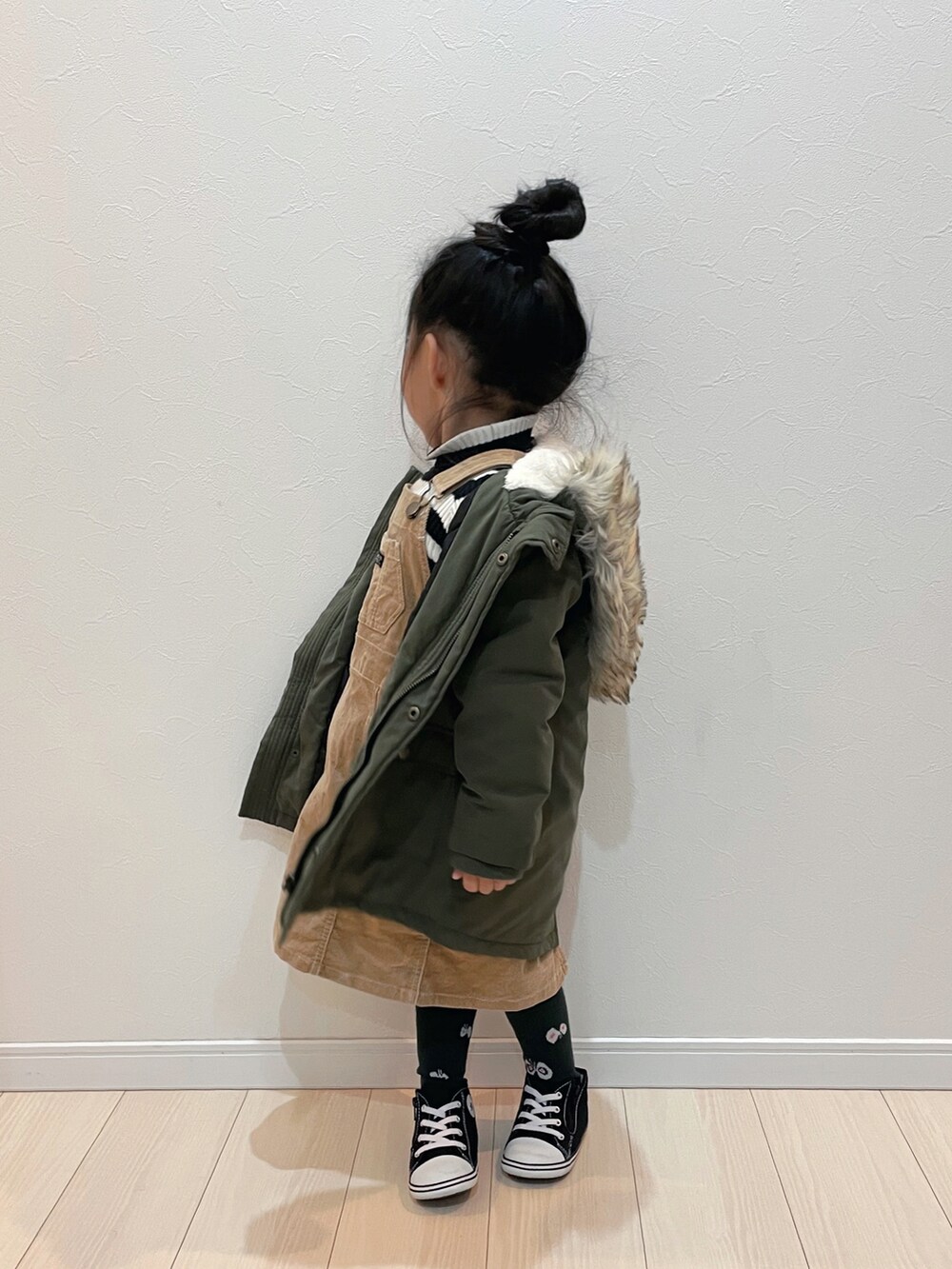 ベージュ系のジャンパースカート、グリーン系のモッズコート、ブラック系のスニーカーを着用したキッズの冬コーディネートの2枚目の写真