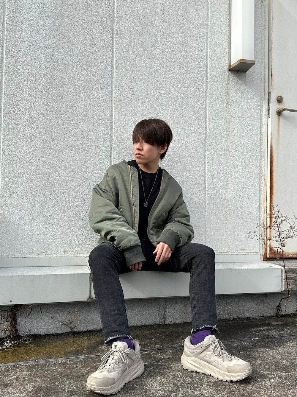 ブラック系のデニムパンツ、グリーン系のMA-1、ブラック系のTシャツ/カットソーを着用したメンズの冬コーディネートの2枚目の写真