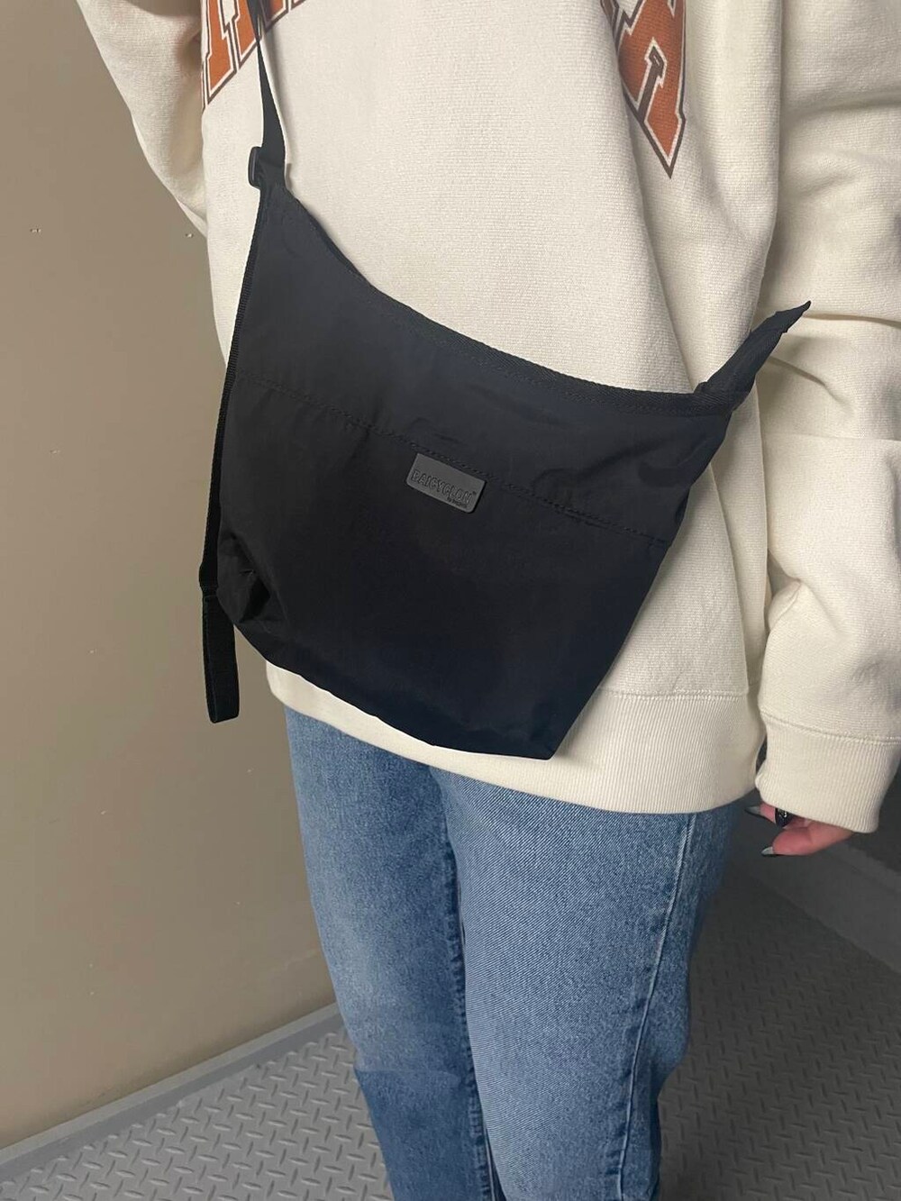 ホワイト系のスニーカー、ブラック系のショルダーバッグ、ブルー系のデニムパンツを着用したレディースの冬コーディネートの3枚目の写真