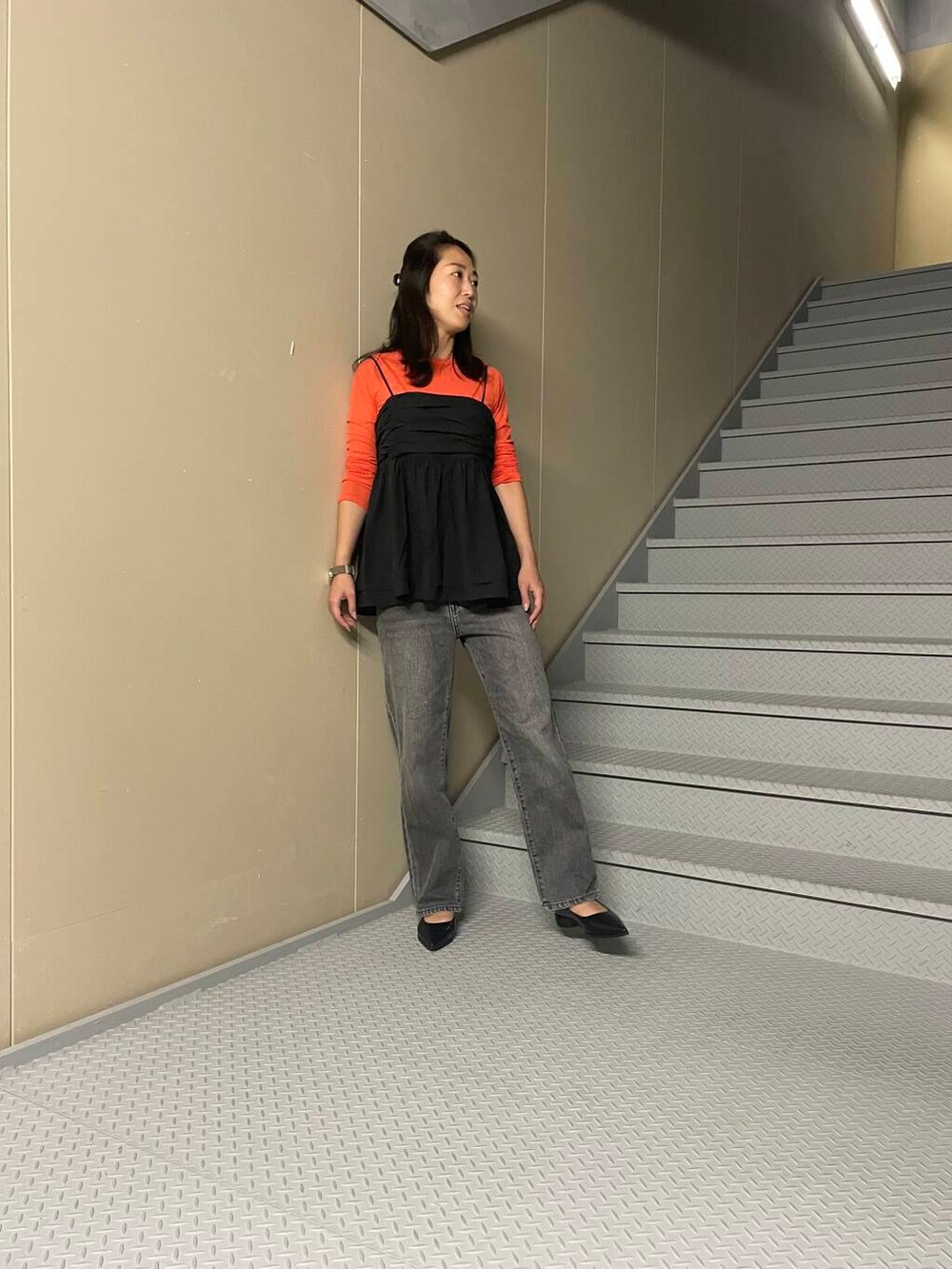 オレンジ系のTシャツ/カットソー、ブラック系のデニムパンツ、ブラック系のキャミソールを着用したレディースの夏コーディネートの2枚目の写真