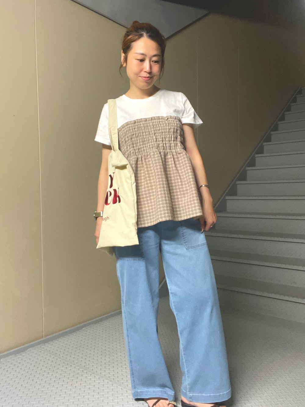 ベージュ系のTシャツ/カットソー、ブルー系のデニムパンツ、ホワイト系のトートバッグを着用したレディースの夏コーディネートの2枚目の写真