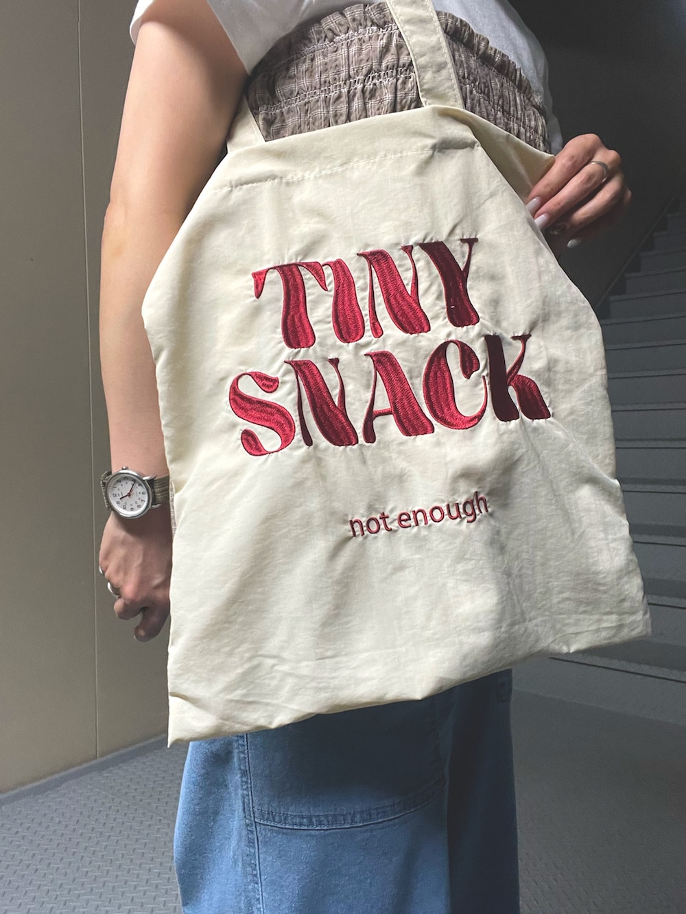 ベージュ系のTシャツ/カットソー、ブルー系のデニムパンツ、ホワイト系のトートバッグを着用したレディースの夏コーディネートの3枚目の写真