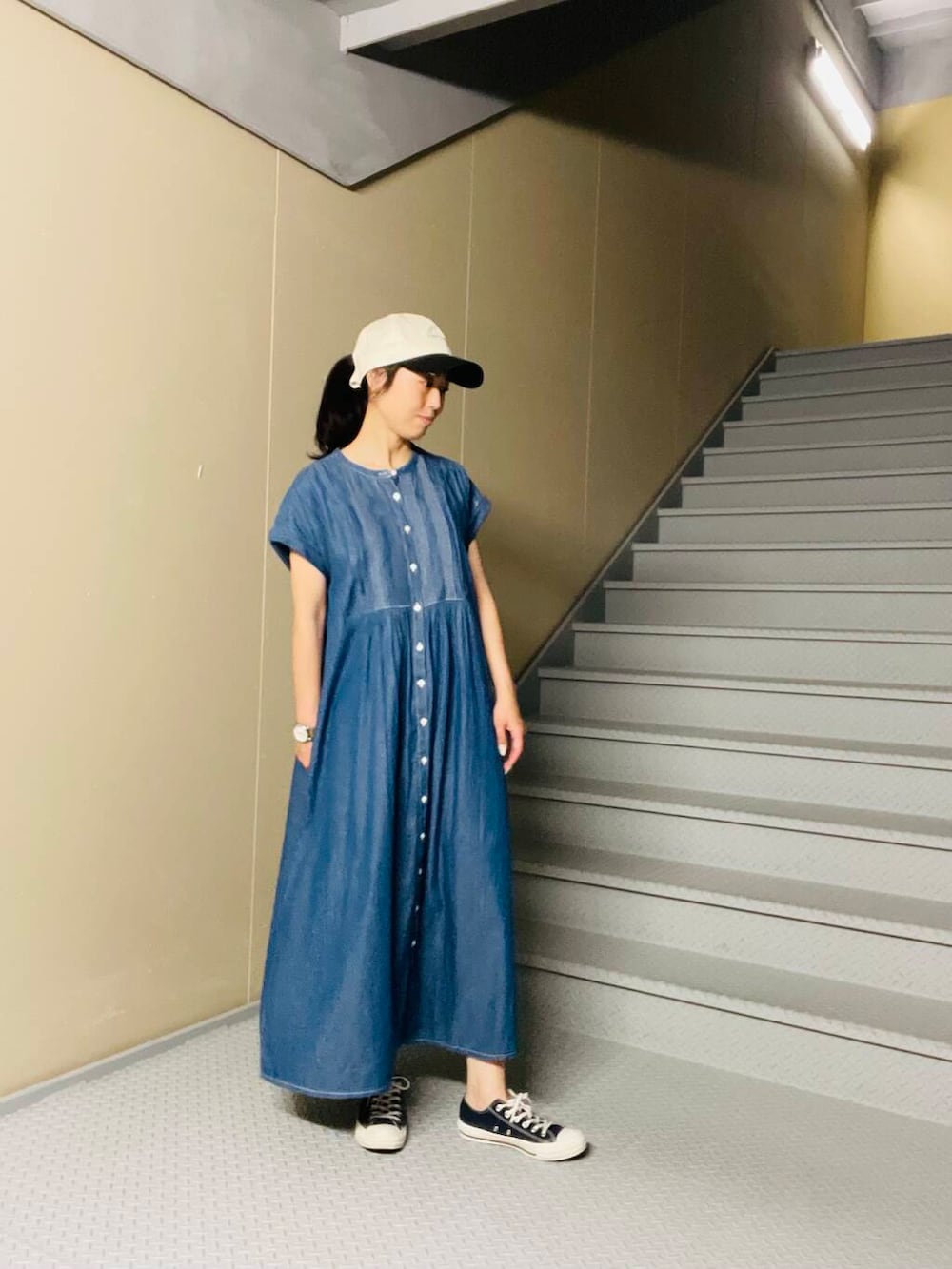 ブルー系のスニーカー、ブルー系のワンピース、ブラック系のキャップを着用したレディースの夏コーディネートの2枚目の写真