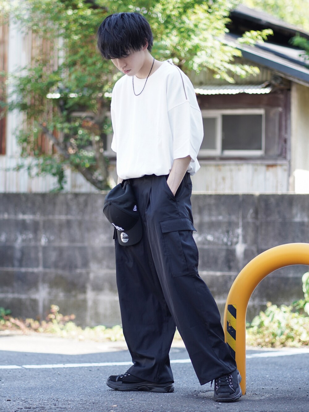 ブラック系のスニーカー、ホワイト系のTシャツ/カットソー、ブラック系のカーゴパンツを着用したメンズの夏コーディネートの2枚目の写真