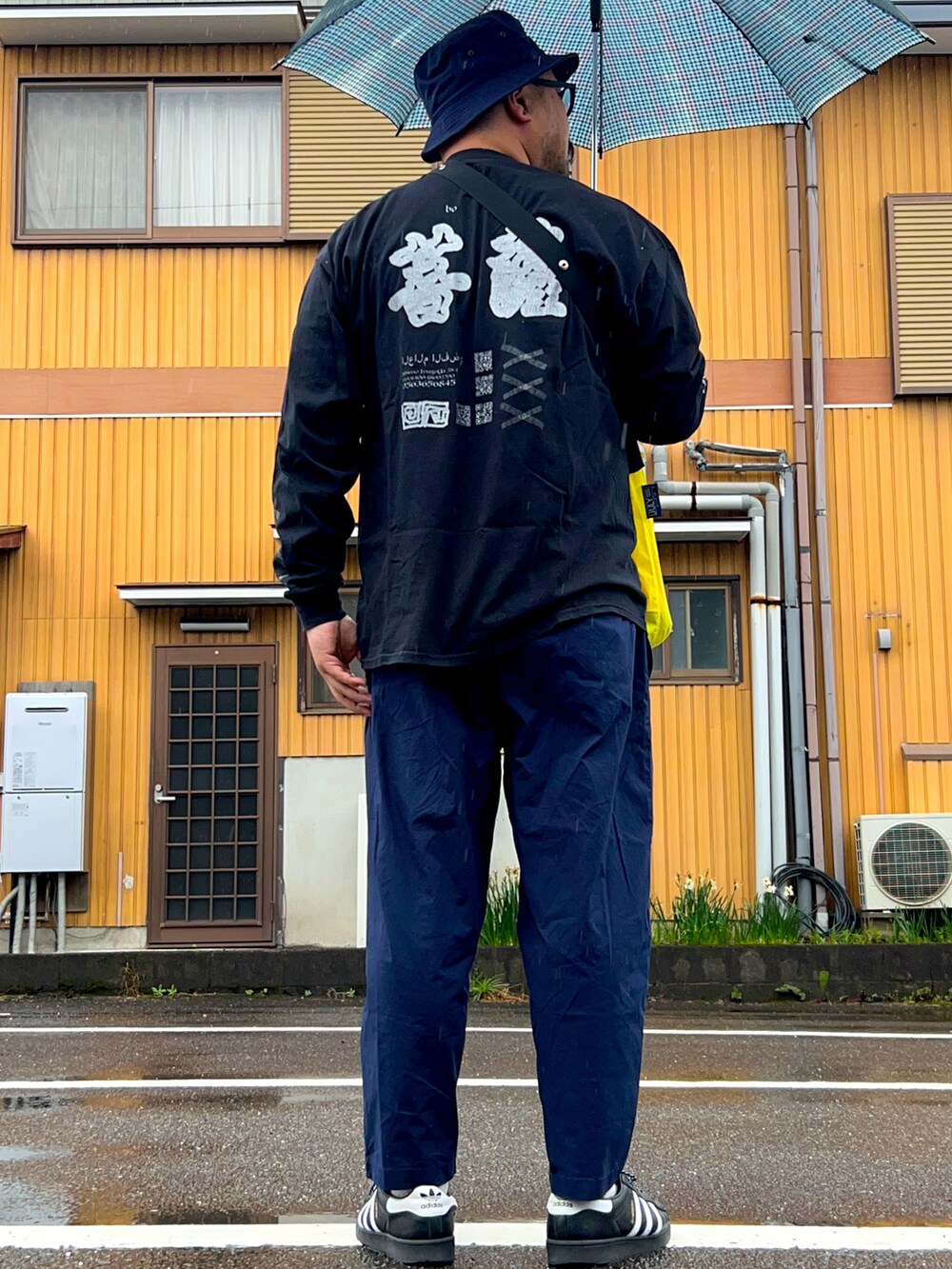 イエロー系のショルダーバッグ、ブラック系のTシャツ/カットソー、ブルー系のパンツを着用したメンズの春コーディネートの2枚目の写真