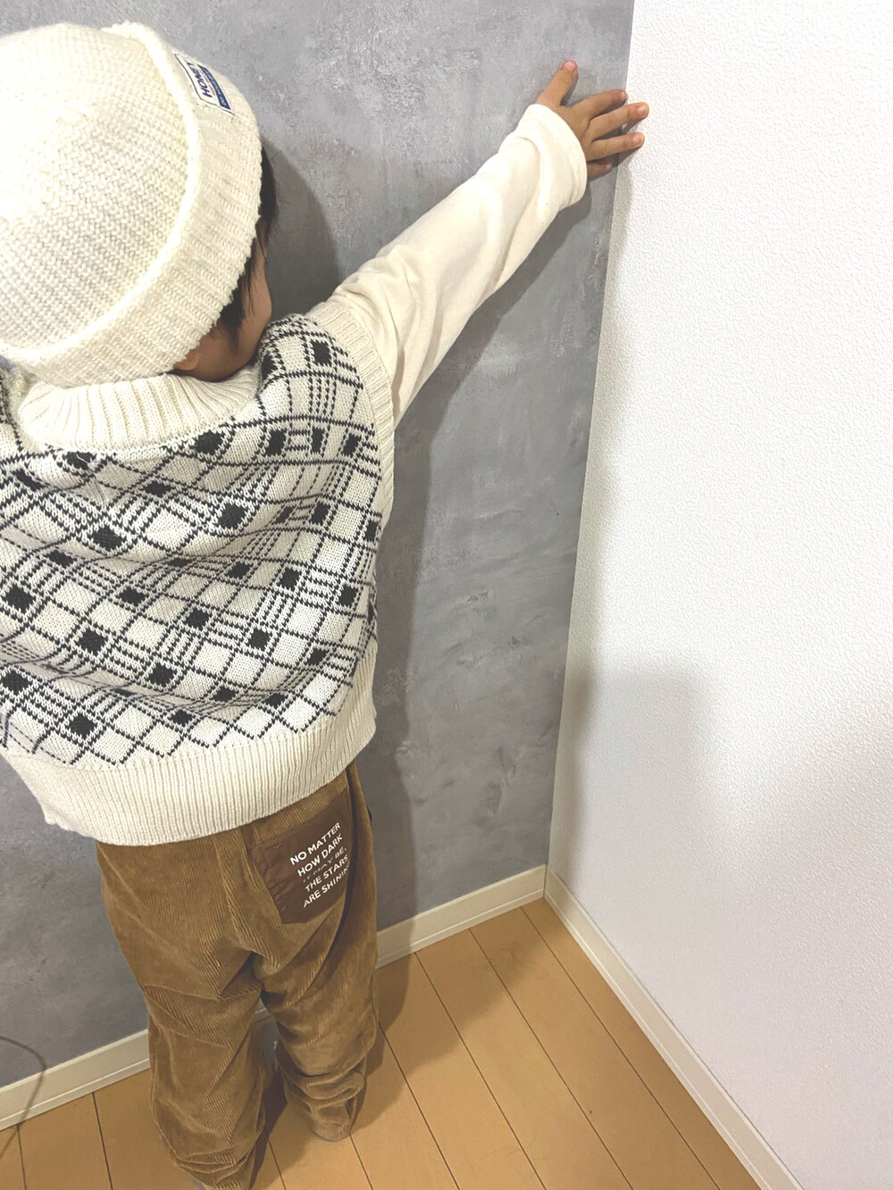 ホワイト系のベスト、ブラウン系のパンツ、ホワイト系の帽子を着用したキッズの冬コーディネートの2枚目の写真