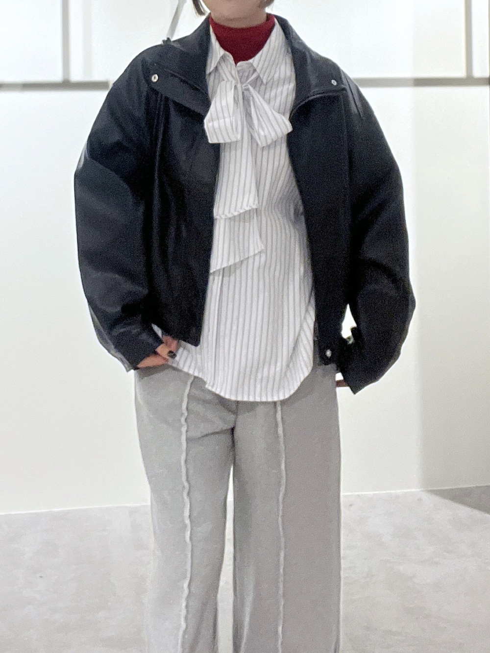 ホワイト系のシャツ/ブラウス、レッド系のニット/セーター、ブラック系のブルゾンを着用したレディースの冬コーディネートの3枚目の写真