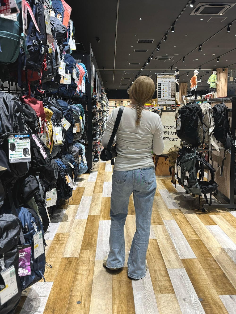 ブラック系のショルダーバッグ、グレー系のTシャツ/カットソー、ブルー系のデニムパンツを着用したレディースの夏コーディネートの3枚目の写真