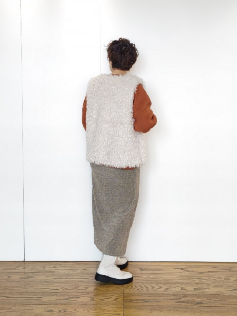 ホワイト系のベスト、オレンジ系のニット/セーター、ベージュ系のスカートを着用したレディースの秋コーディネートの2枚目の写真