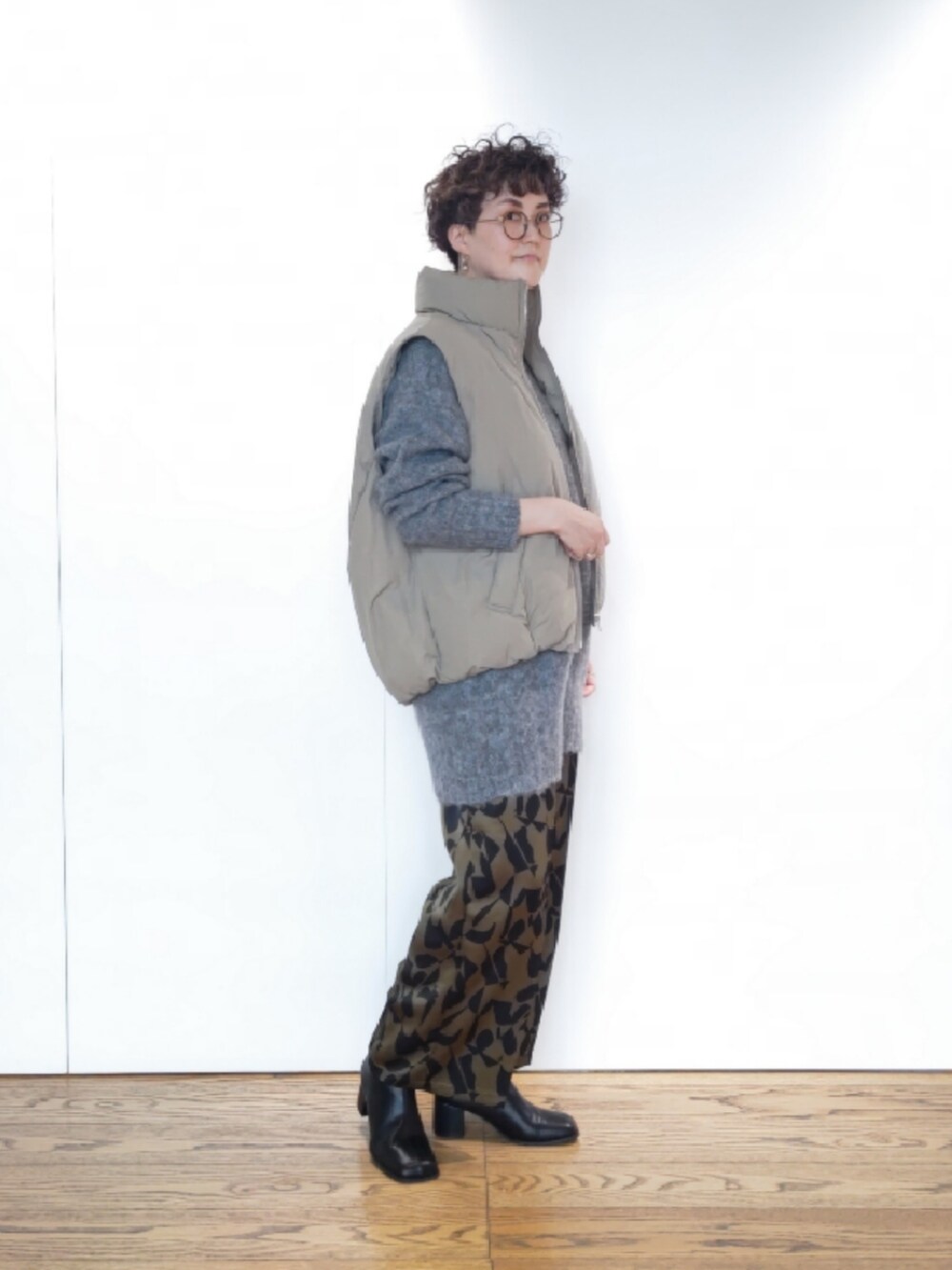 グリーン系のハンドバッグ、グレー系のニット/セーター、ブラック系のブーツを着用したレディースの冬コーディネートの2枚目の写真