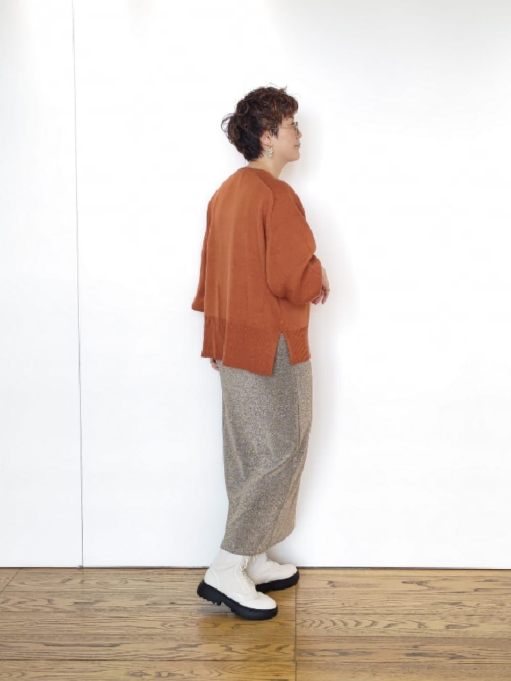 ホワイト系のベスト、オレンジ系のニット/セーター、ベージュ系のスカートを着用したレディースの秋コーディネートの4枚目の写真