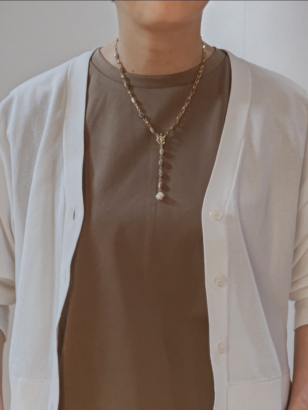 ブラウン系のスカート、オレンジ系のサンダル、ホワイト系のハンドバッグを着用したレディースの夏コーディネートの2枚目の写真