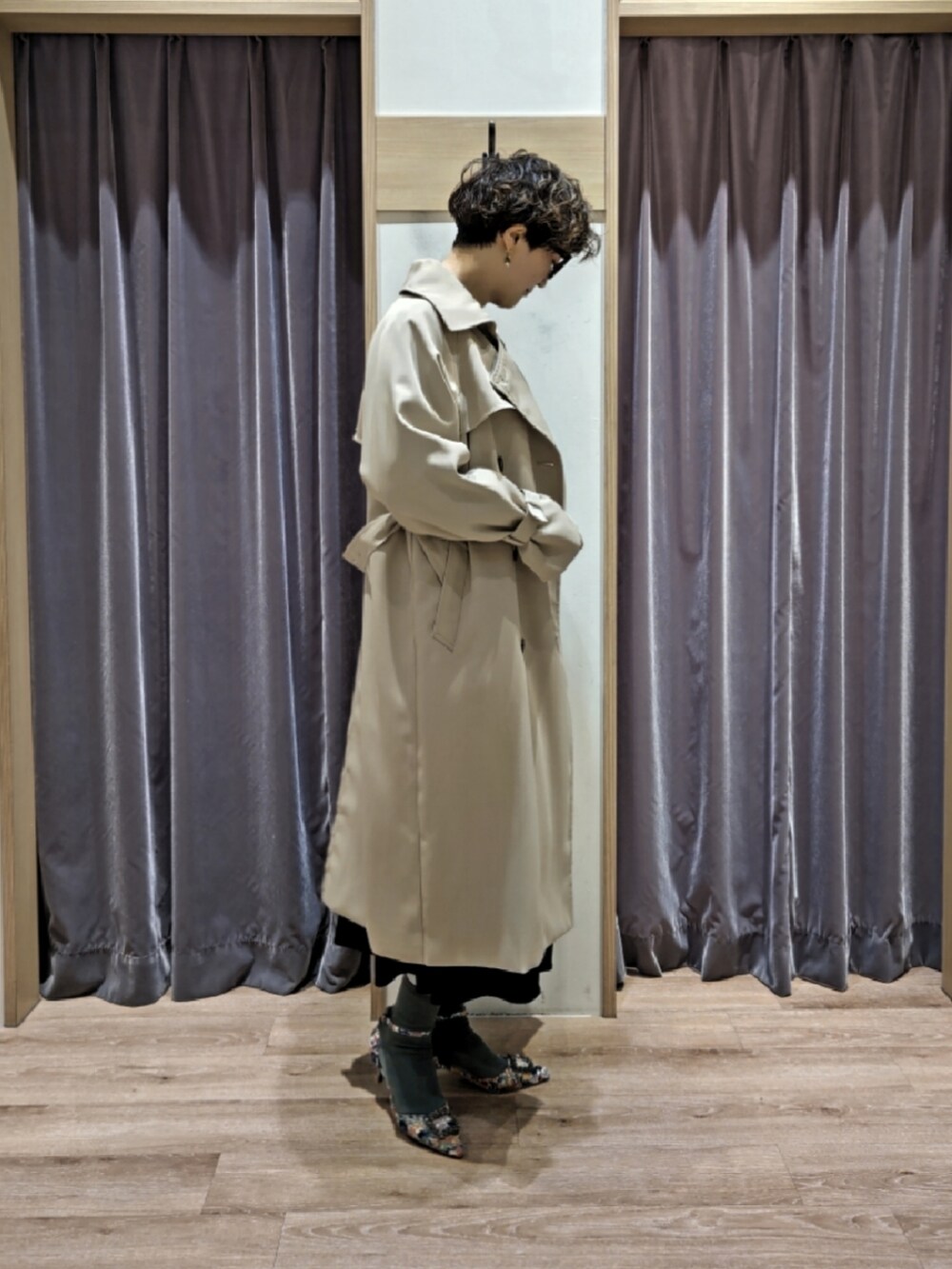 ブルー系のワンピース、ブラウン系のハンドバッグ、ホワイト系のパンプスを着用したレディースの冬コーディネートの2枚目の写真