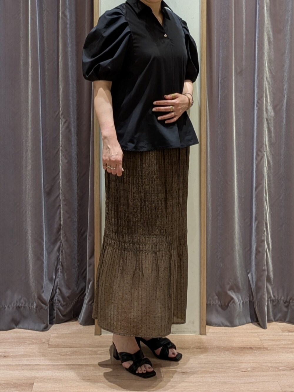 グリーン系のハンドバッグ、ホワイト系のノーカラージャケット、ブラック系のサンダルを着用したレディースの春コーディネートの2枚目の写真