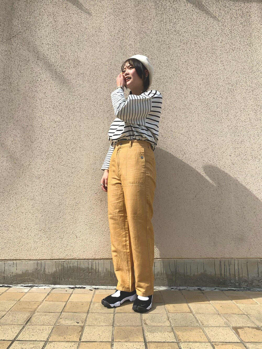 ホワイト系のトップス、イエロー系のパンツ、ブラック系のスニーカーを着用したレディースの春コーディネートの2枚目の写真