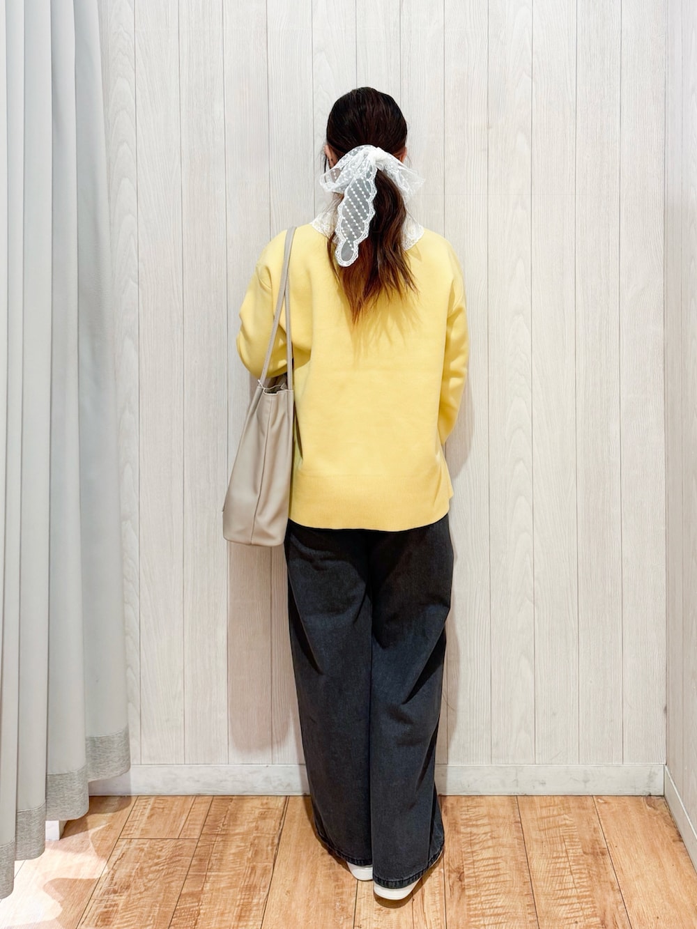 イエロー系のニット/セーター、ブラック系のデニムパンツ、シルバー系のスニーカーを着用したレディースの冬コーディネートの3枚目の写真