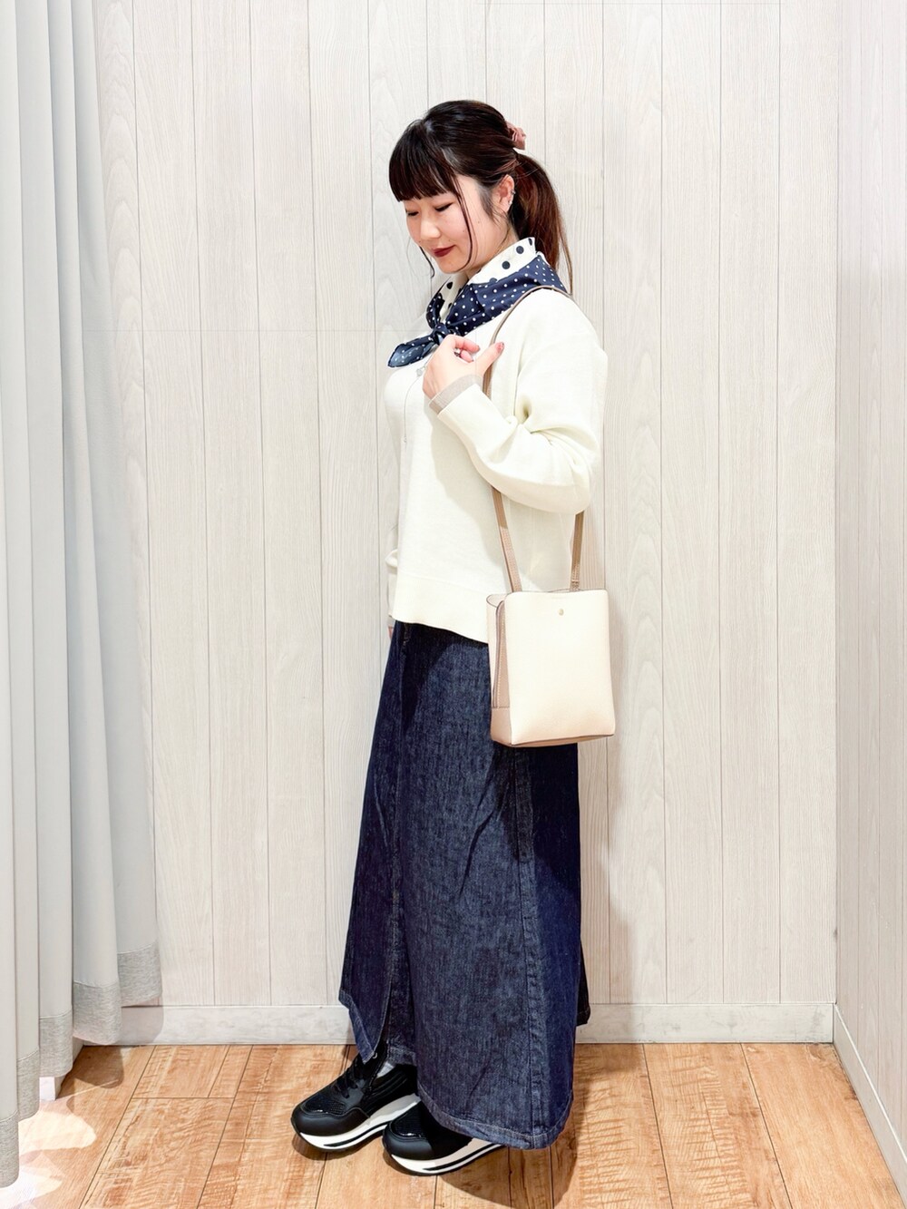 ホワイト系のニット/セーター、ブラック系のスニーカー、ブルー系のデニムスカートを着用したレディースの冬コーディネートの2枚目の写真