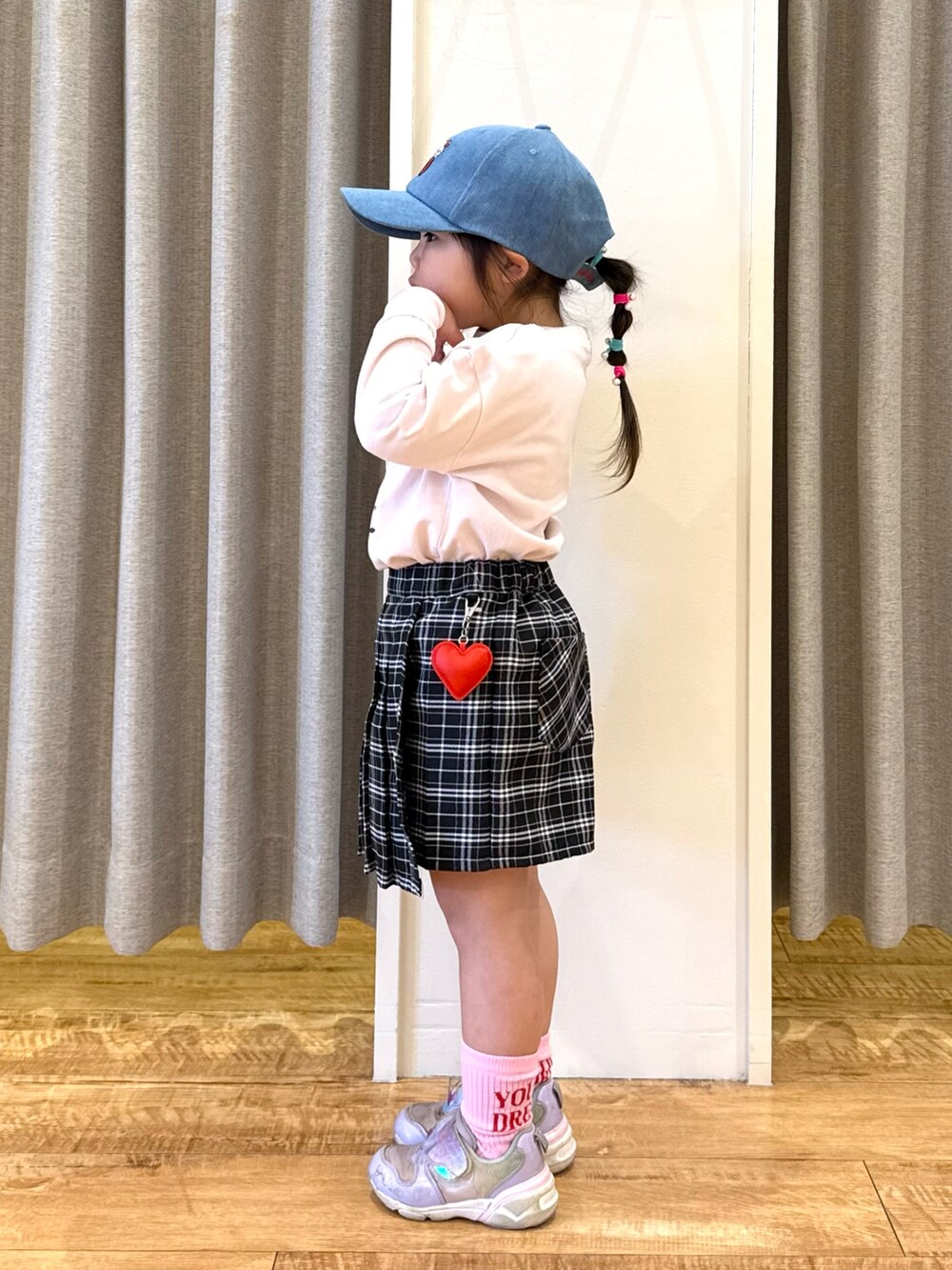 ホワイト系のTシャツ/カットソー、ブラック系のスカート、ブルー系のキャップを着用したキッズの春コーディネートの2枚目の写真