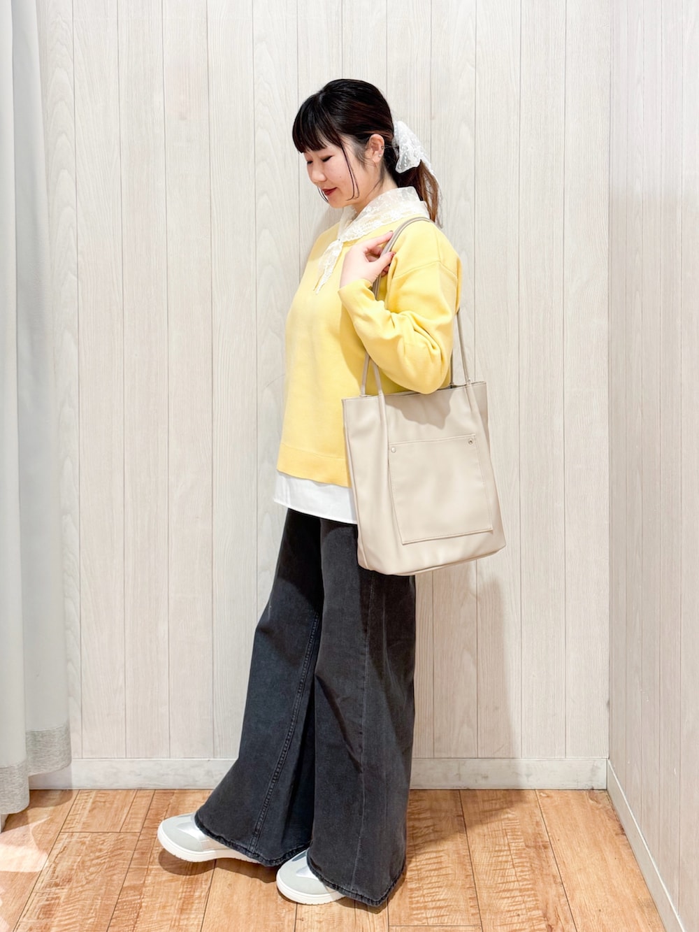 イエロー系のニット/セーター、ブラック系のデニムパンツ、シルバー系のスニーカーを着用したレディースの冬コーディネートの2枚目の写真