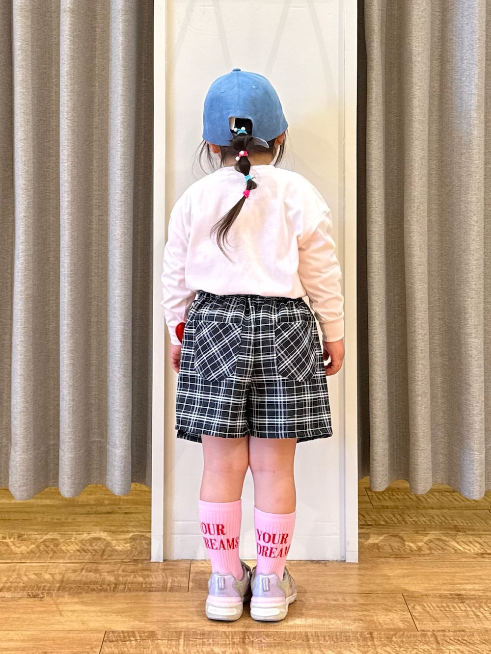 ホワイト系のTシャツ/カットソー、ブラック系のスカート、ブルー系のキャップを着用したキッズの春コーディネートの3枚目の写真