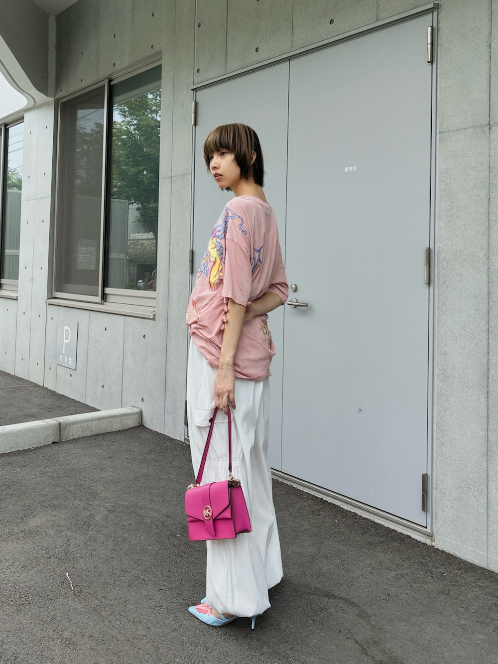 ピンク系のショルダーバッグ、ピンク系のTシャツ/カットソー、ブルー系のパンプスを着用したレディースの夏コーディネートの2枚目の写真